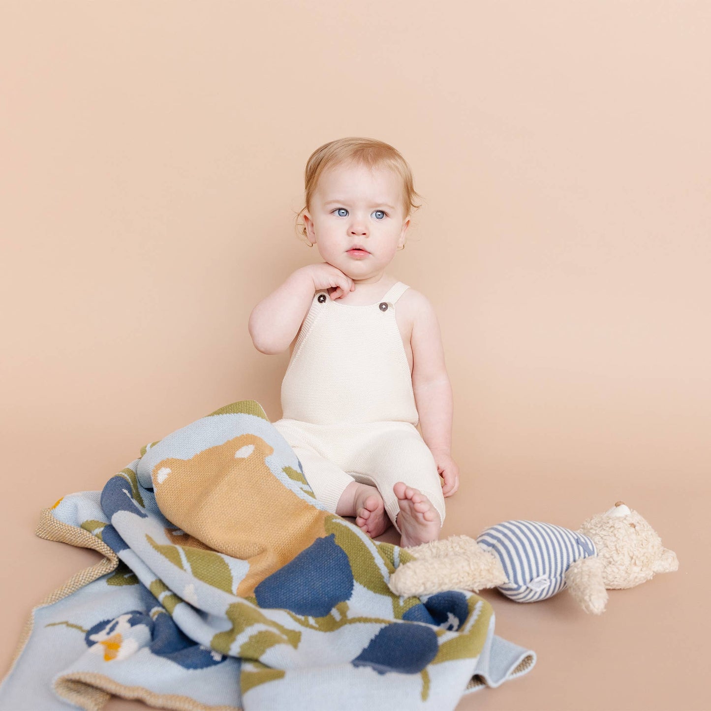 Baby sitting on a blueberry blanket with a beige background