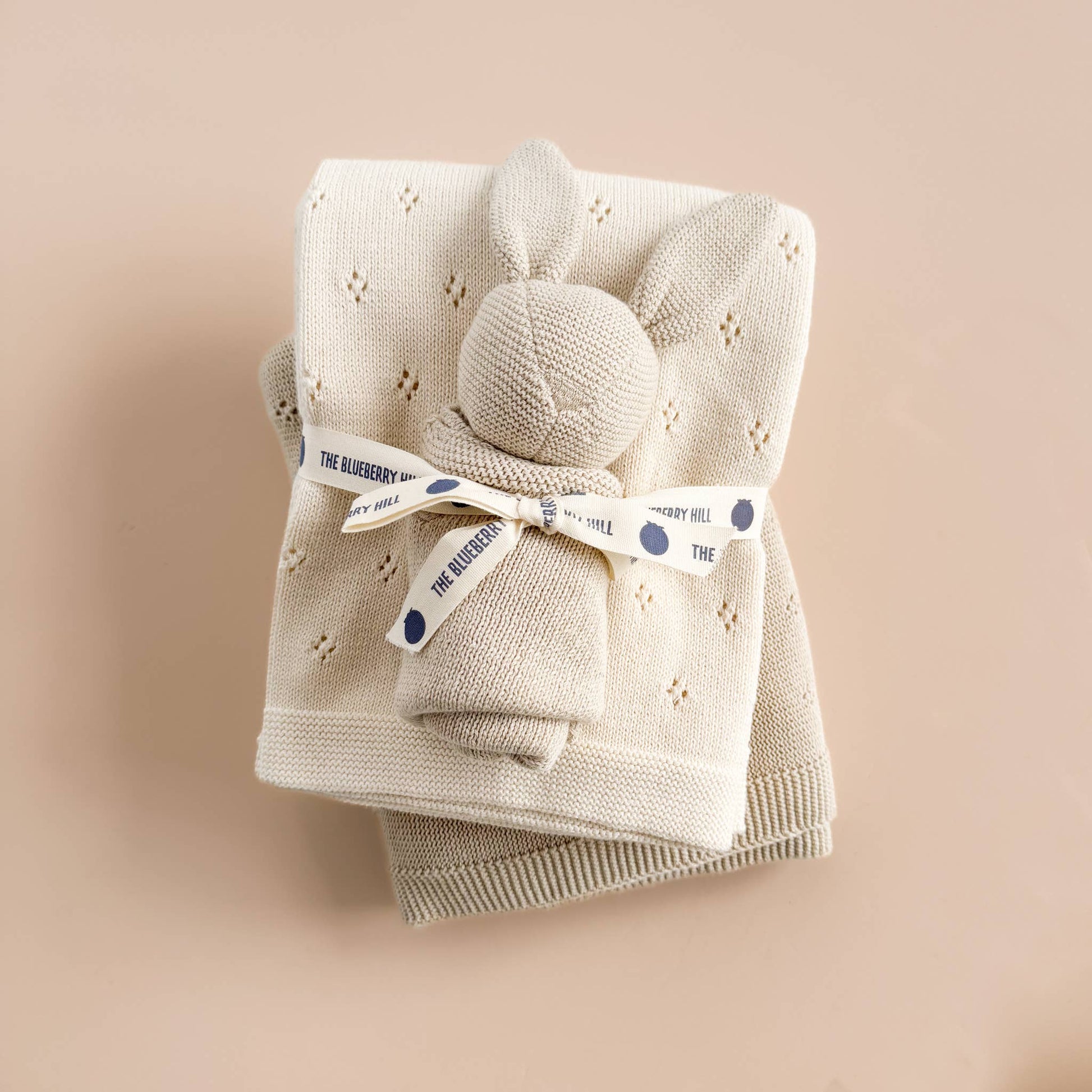 Baby blanket with knitted bunny lovey on a beige background