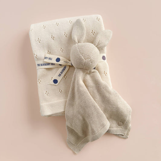 Baby blanket with bunny toy on a pink background