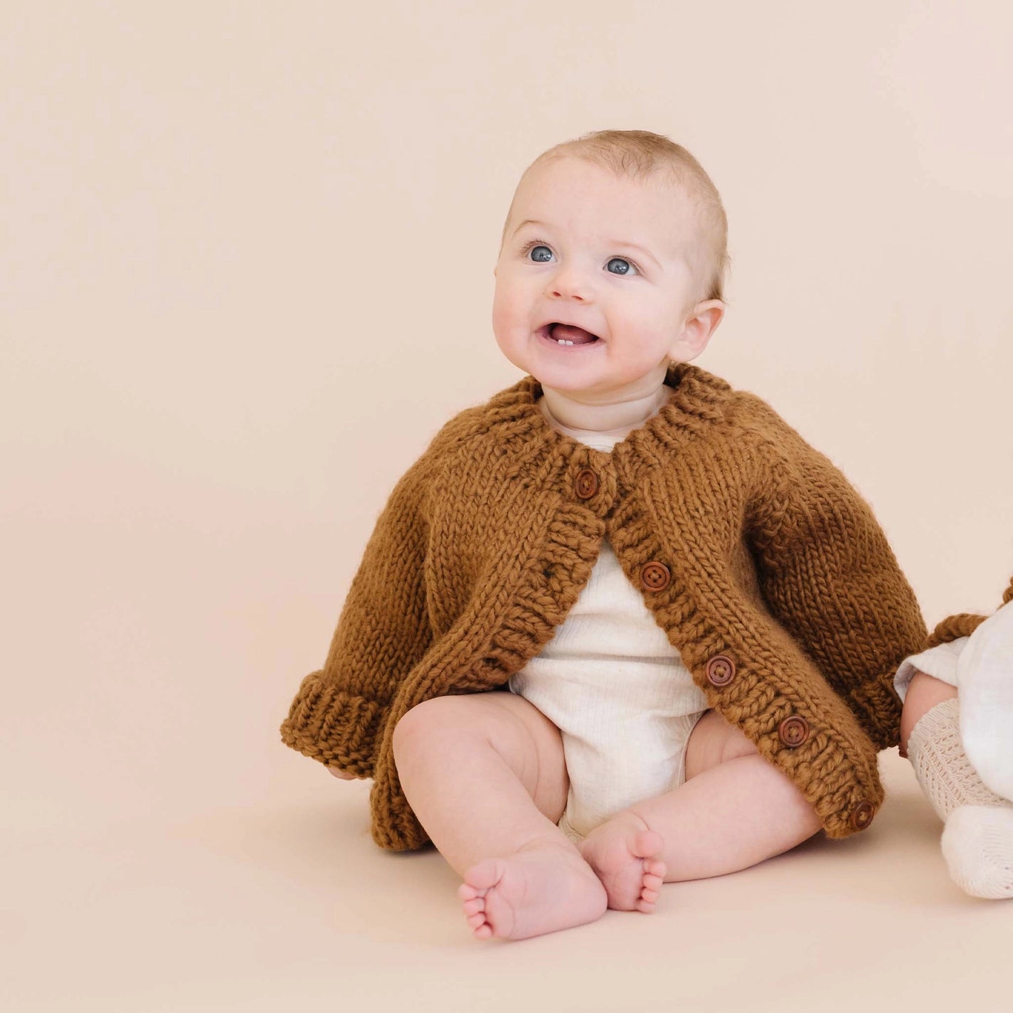 A baby wearing a classic knitted cardigan in walnut