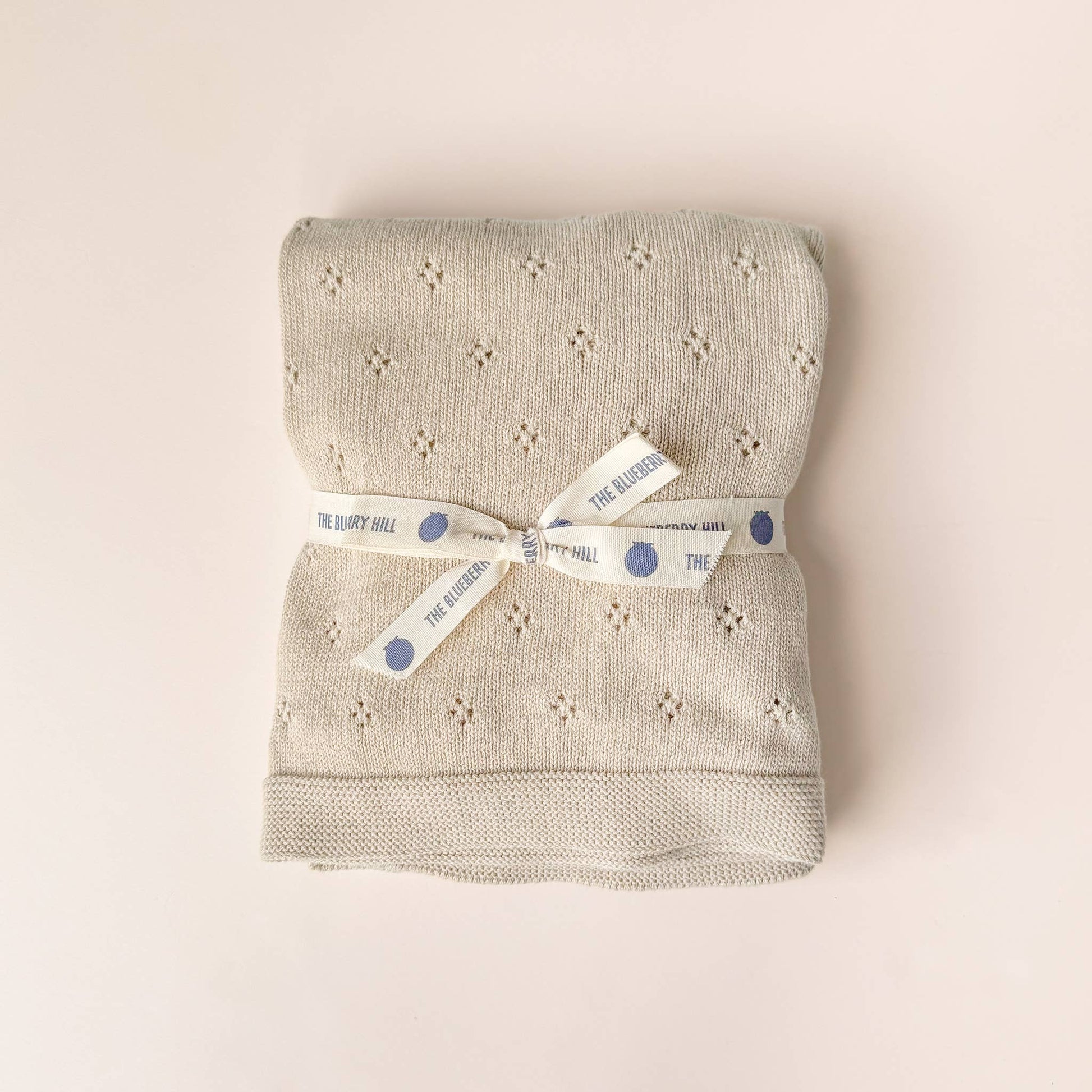 Folded textured blanket with a ribbon on a beige background