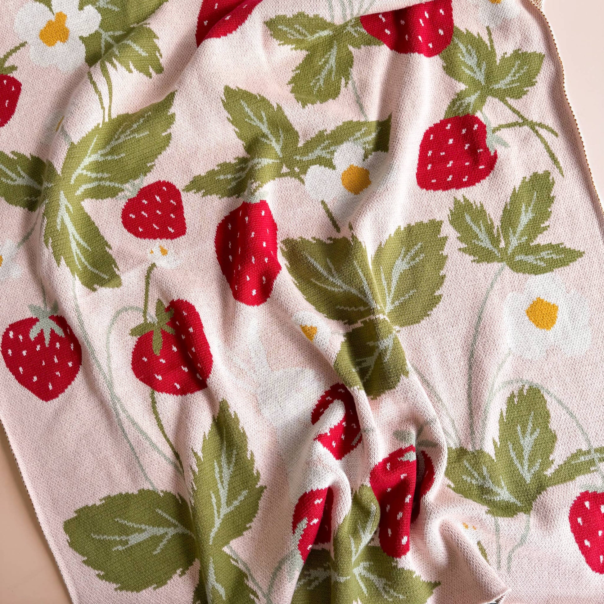 Fabric with strawberry and leaf pattern on a light pink background