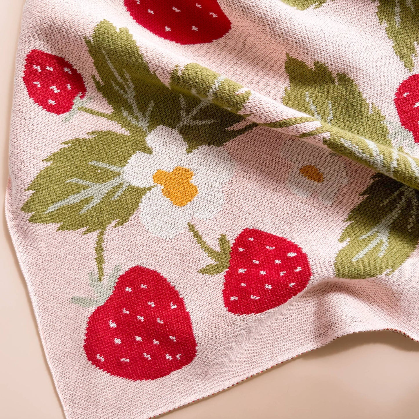 Blanket with strawberry and flower pattern on a light pink background
