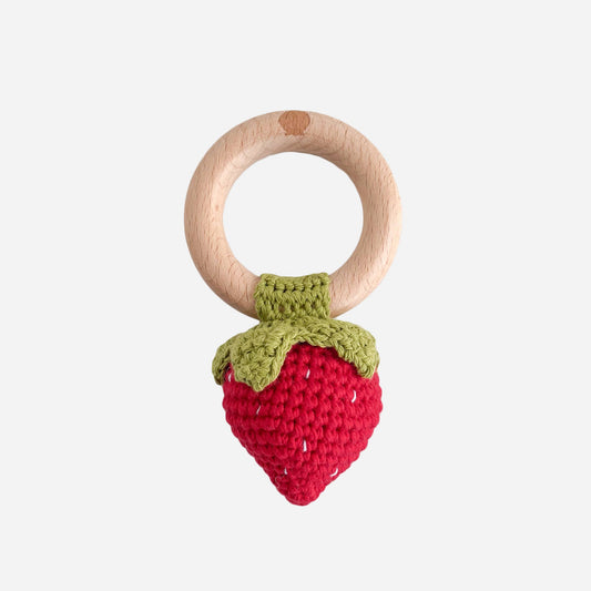 Wooden teething ring with a red strawberry-shaped crochet toy on a white background
