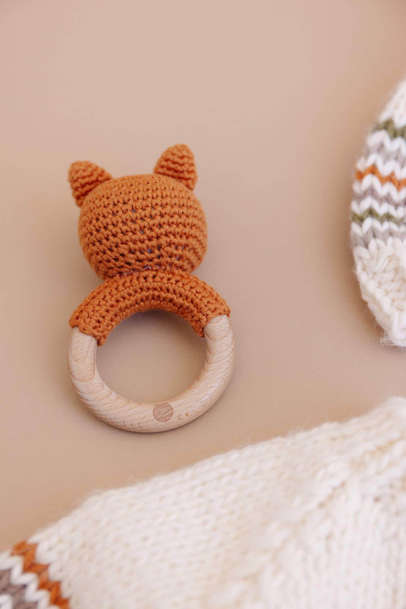 Knitted fox rattle toy on a beige background