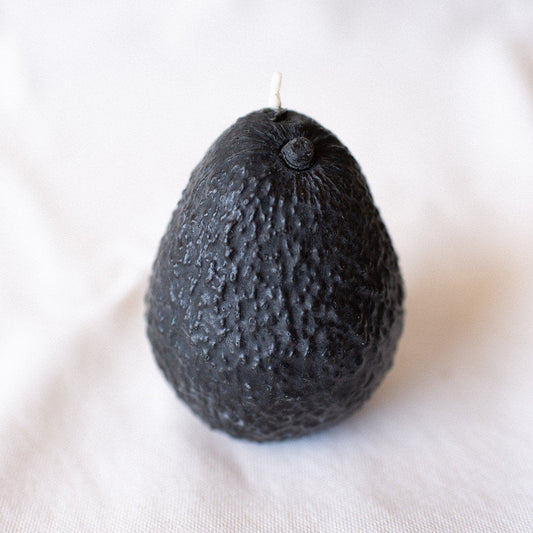 Black avocado-shaped candle on a white background