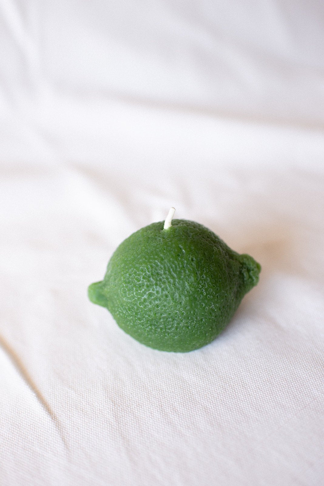 Green candle shaped like a lime on a white background