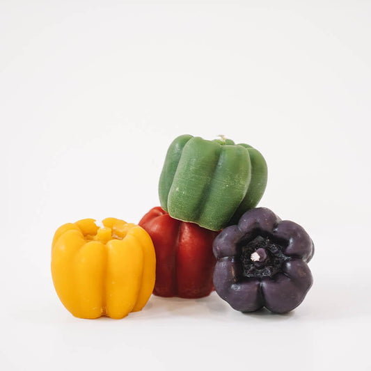 Four colorful bell pepper-shaped candles on a white background