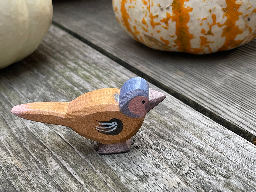 chaffinch hand carved hand painted by ostheimer toys on a weathered wood with striped pumpkins int he back ground