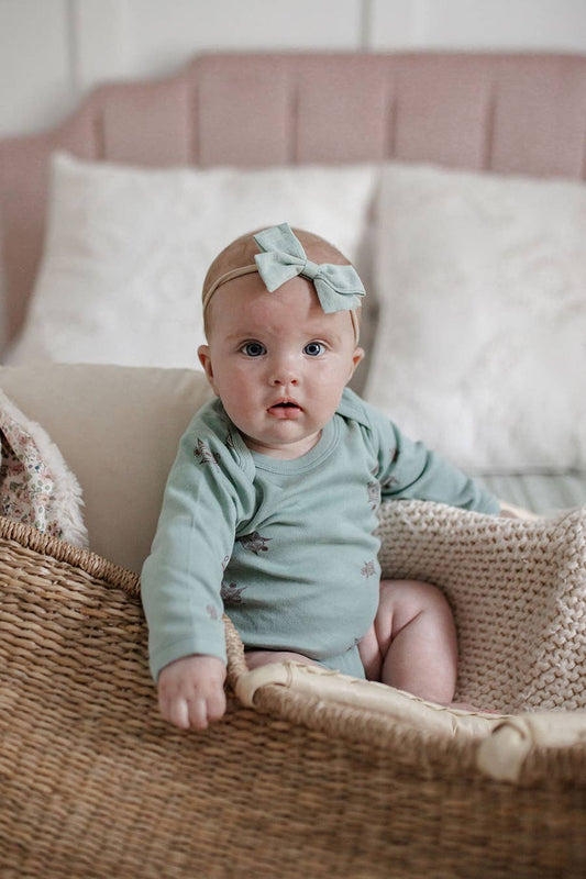 a baby sitting in a crib wearing a long-sleeve turtle print onesie