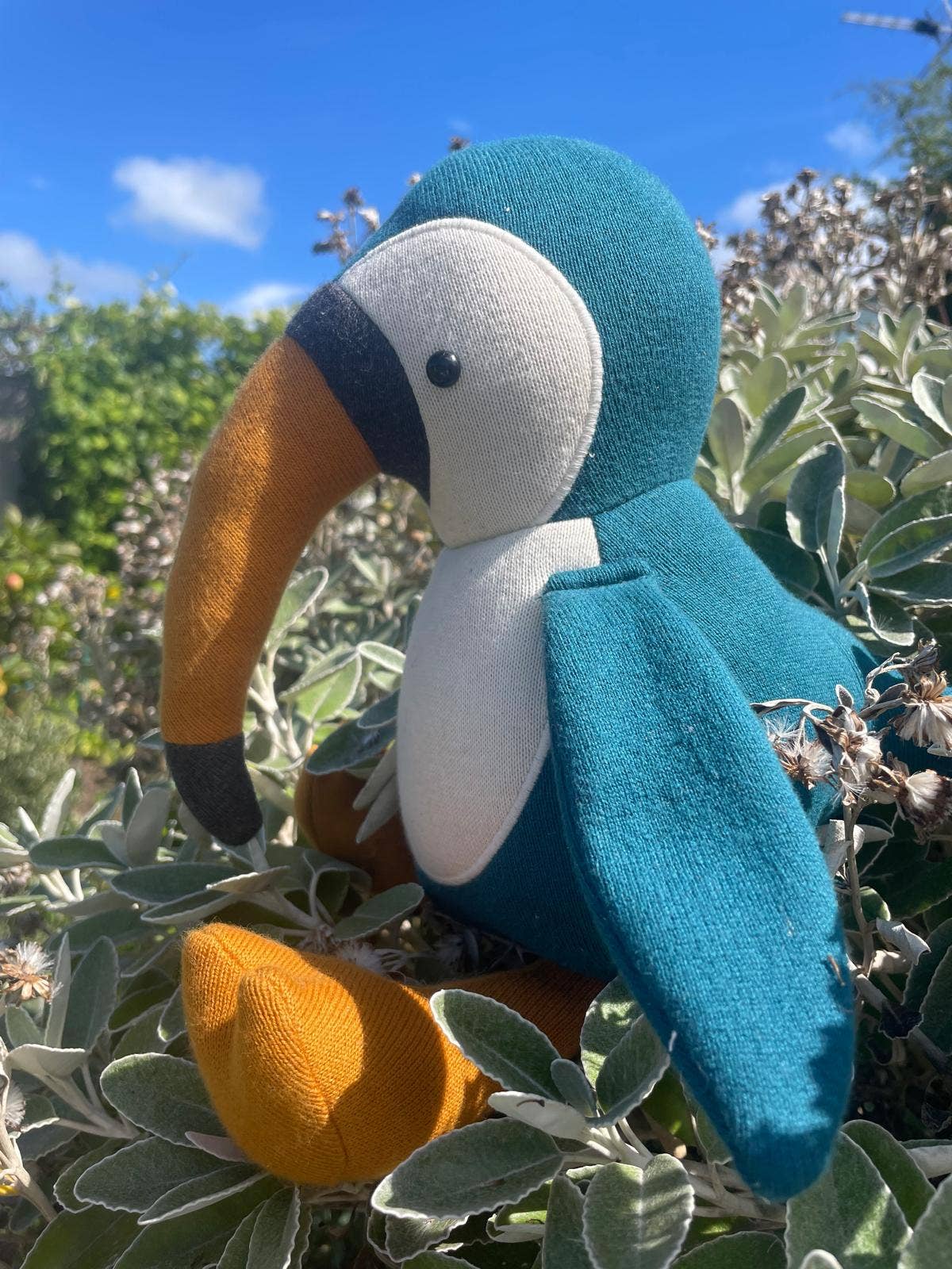 a blue organic stuff toucan sitting in foliage