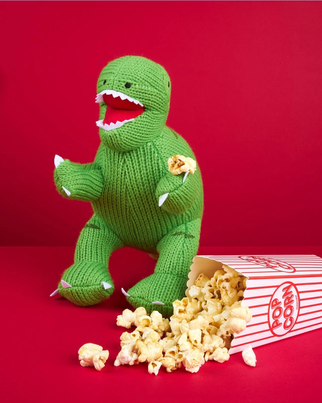 green t-rex knitted plush toy with popcorn