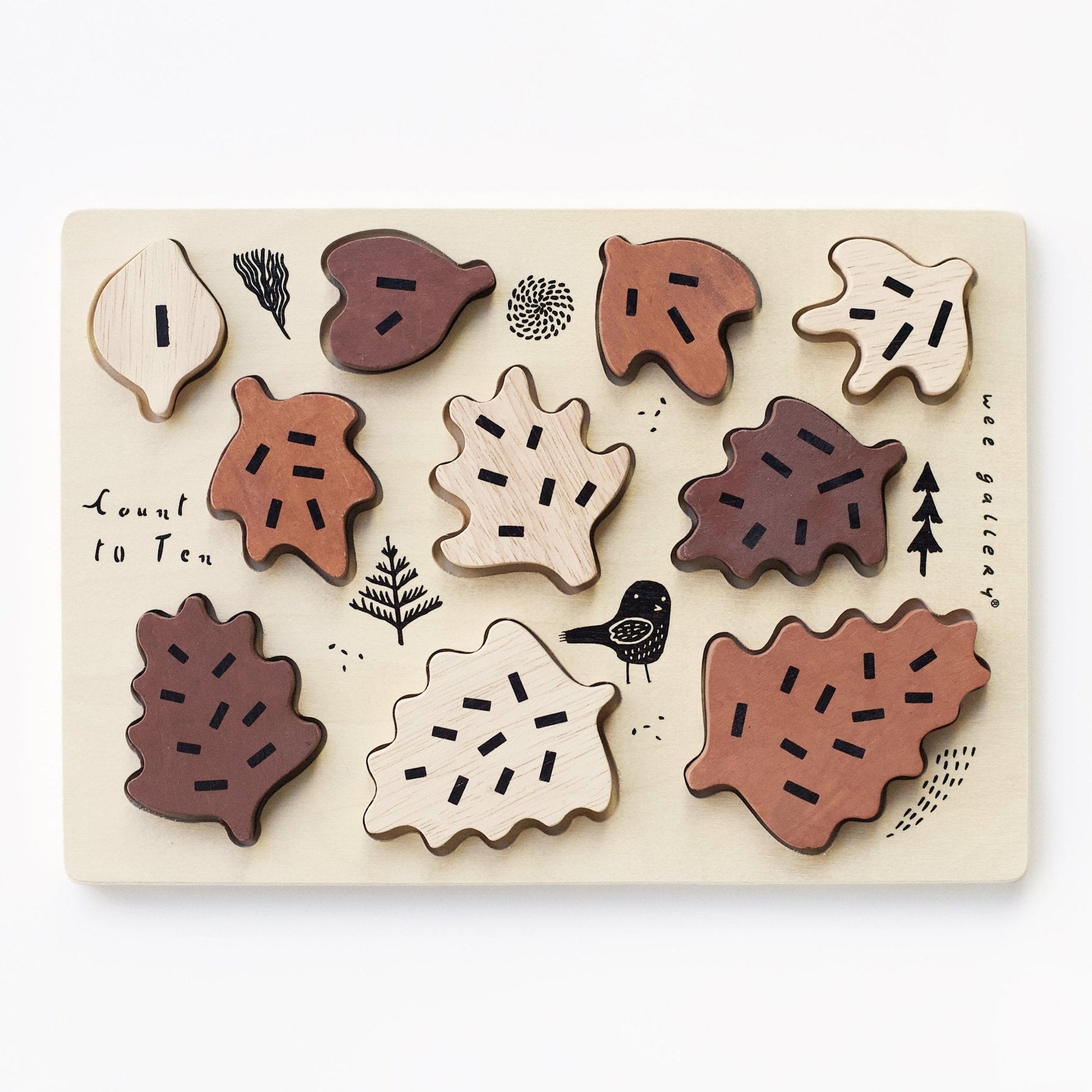 Wooden leaf-shaped puzzle on a light wooden board with nature-themed illustrations.