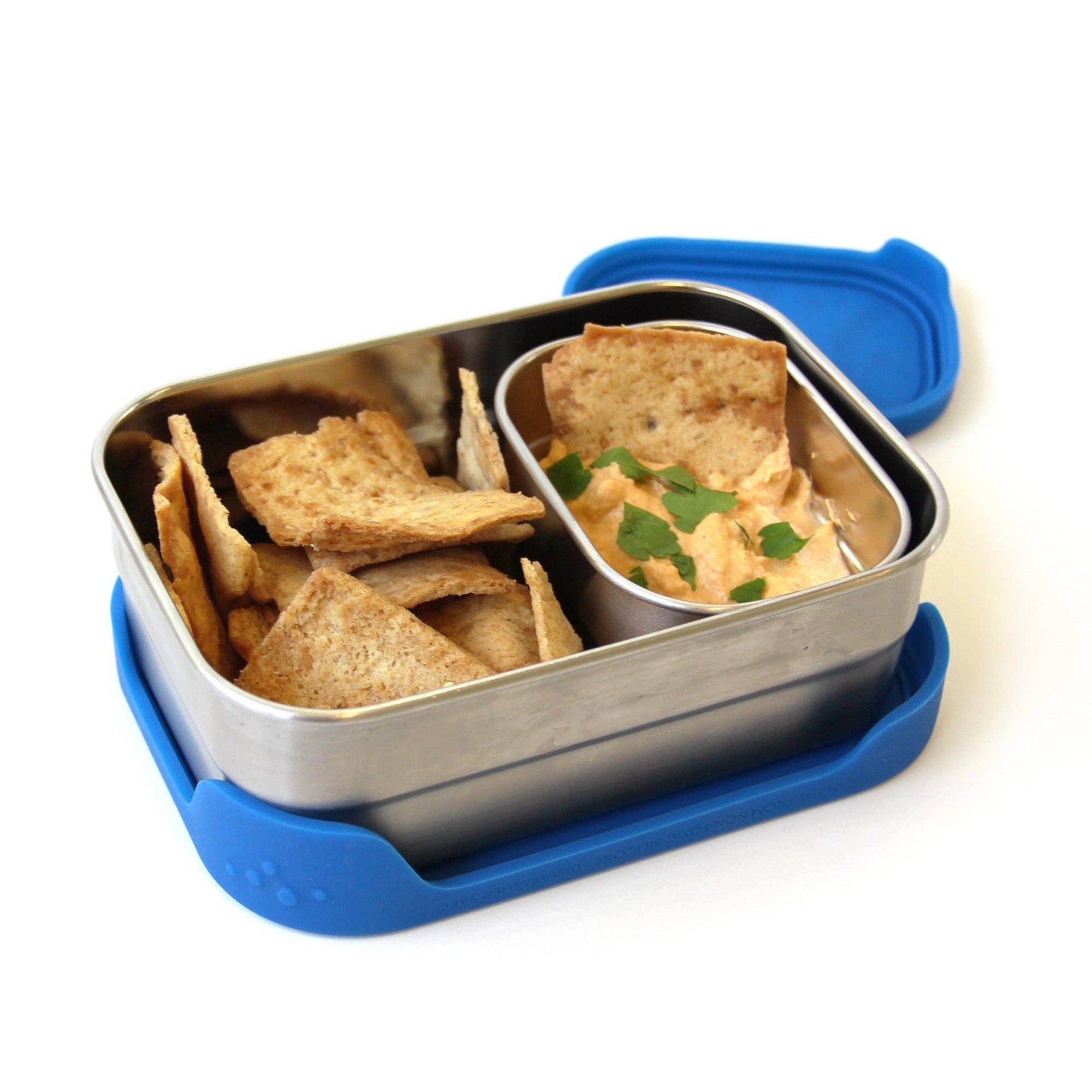 Metal lunch box with blue lid containing crackers and a small container of dip on a white background
