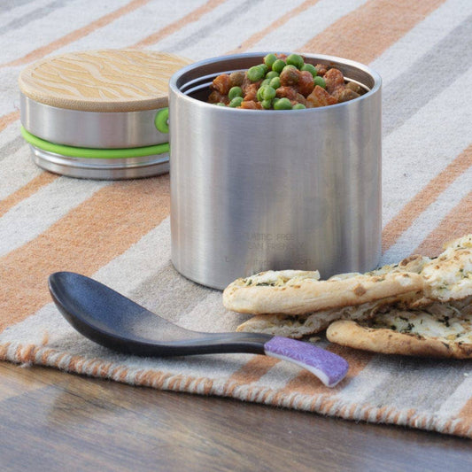 Stainless steel food container with snacks on a striped tablecloth