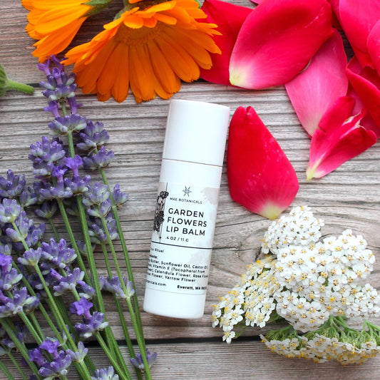 Garden flowers lip balm on a wooden table surrounded by flowers petals