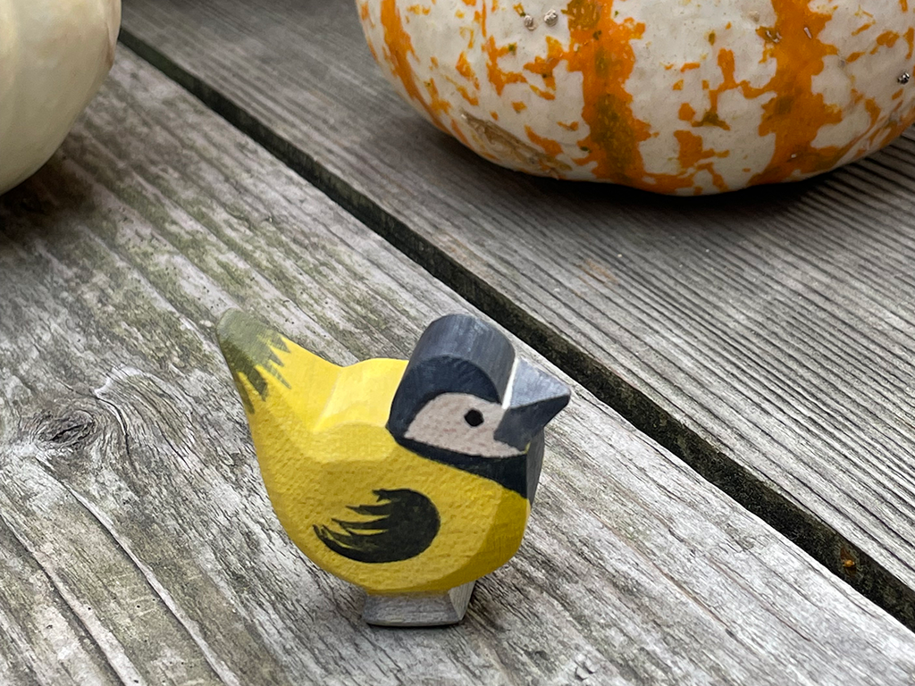 Goldfinch hand carved hand painted by ostheimer toys on a weathered wood with striped pumpkins int he back ground