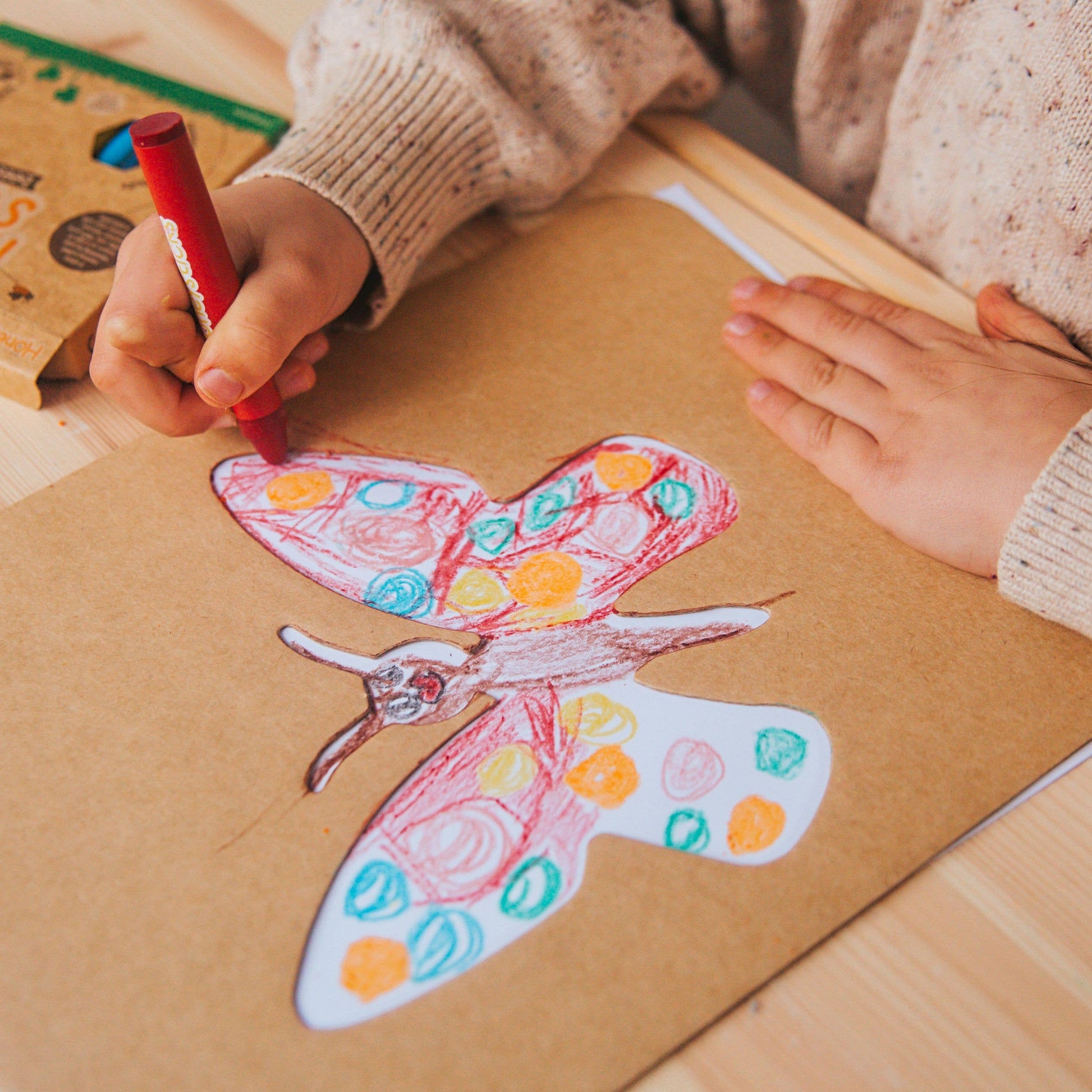 Close up of child's hands drawing a butterfly with a cardboard stencil