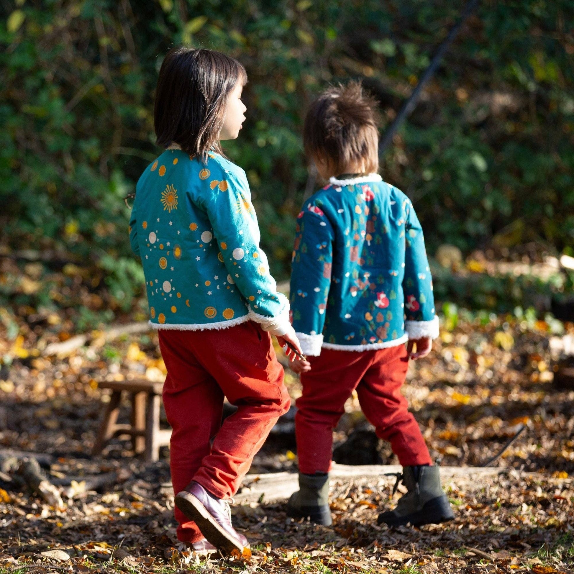 two kids walking in the woods wearing patterned reversible jacket