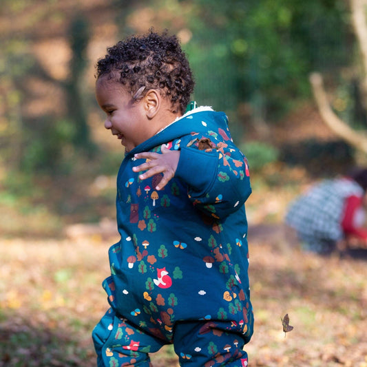 Toddler running outside wearing an enchanted forest sherpa-lined snowsuit