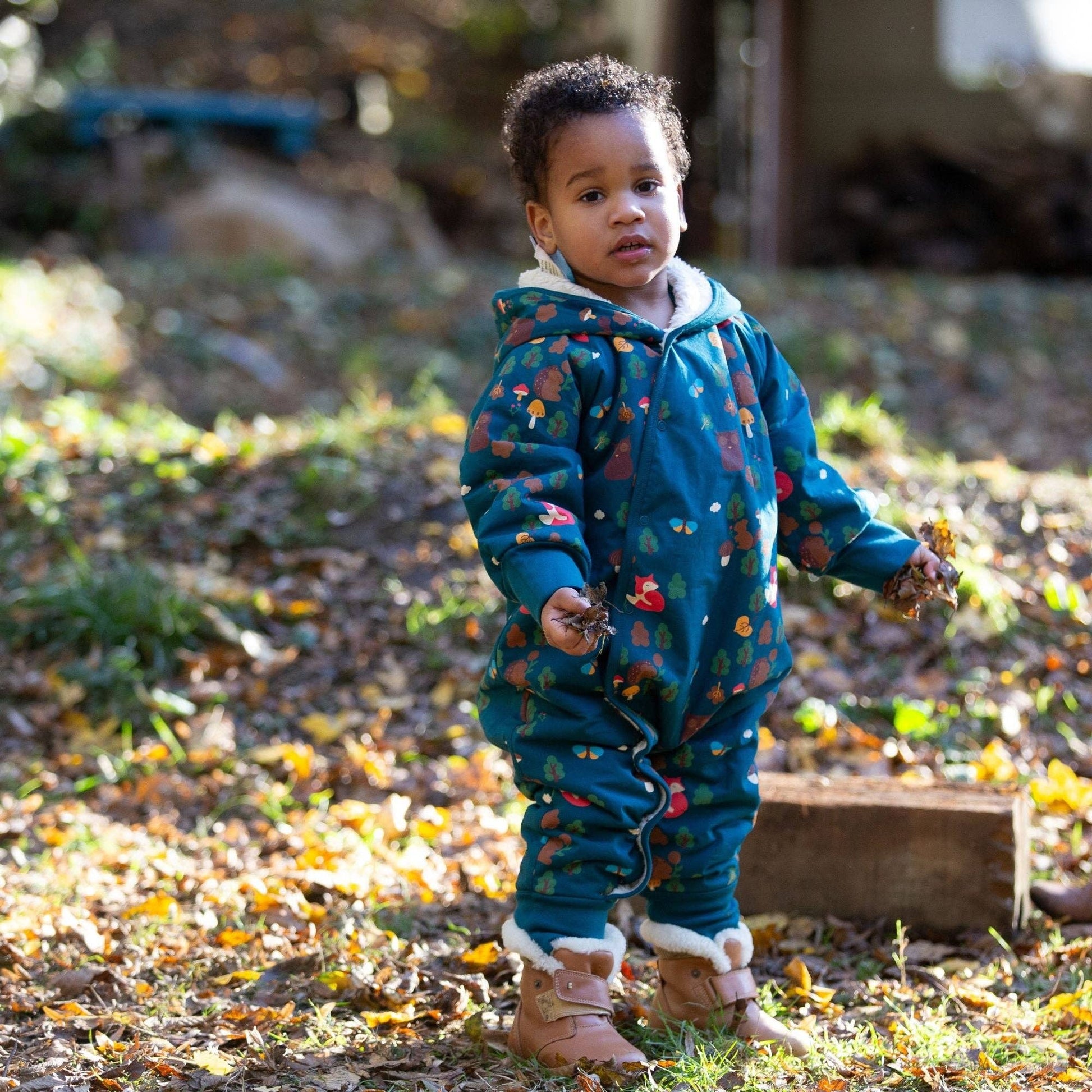 Toddler standing outdoors wearing an enchanted forest sherpa-lined snowsuit