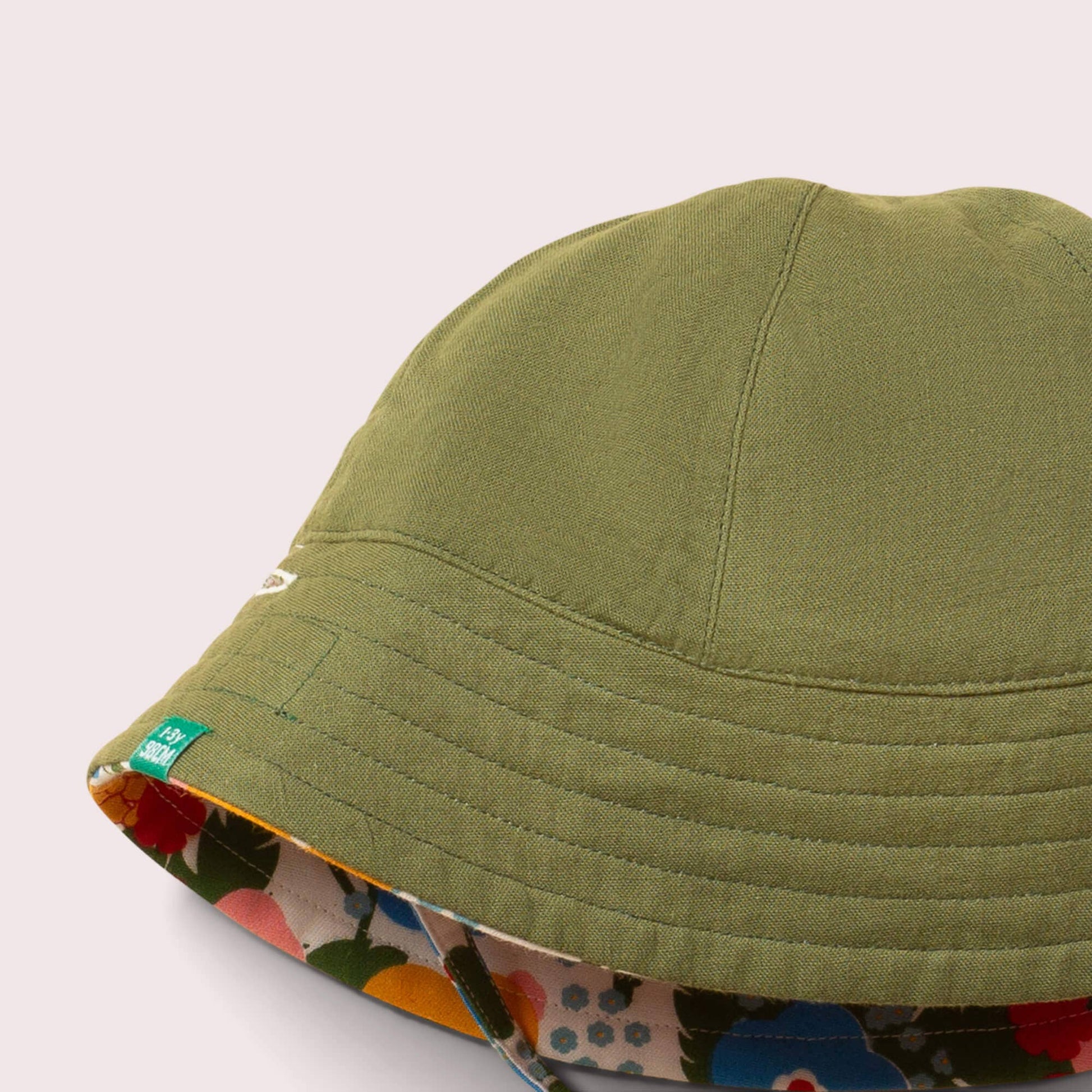 Close-up of a green sun hat with a floral interior lining on a light gray background