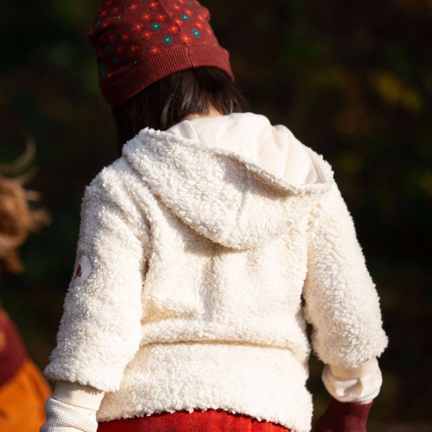 Child with their back turned to the camera wearing a hooded sherpa fleece jacket