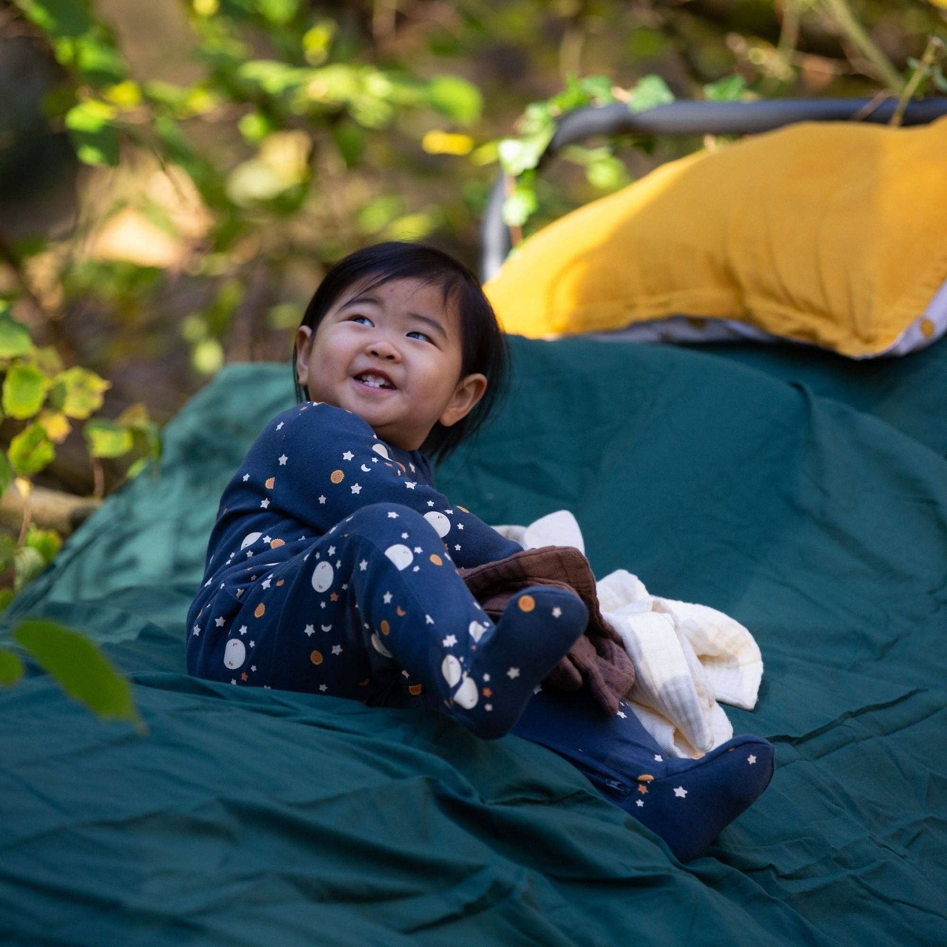 baby sitting on a blanket outside wearing over the moon organic footie