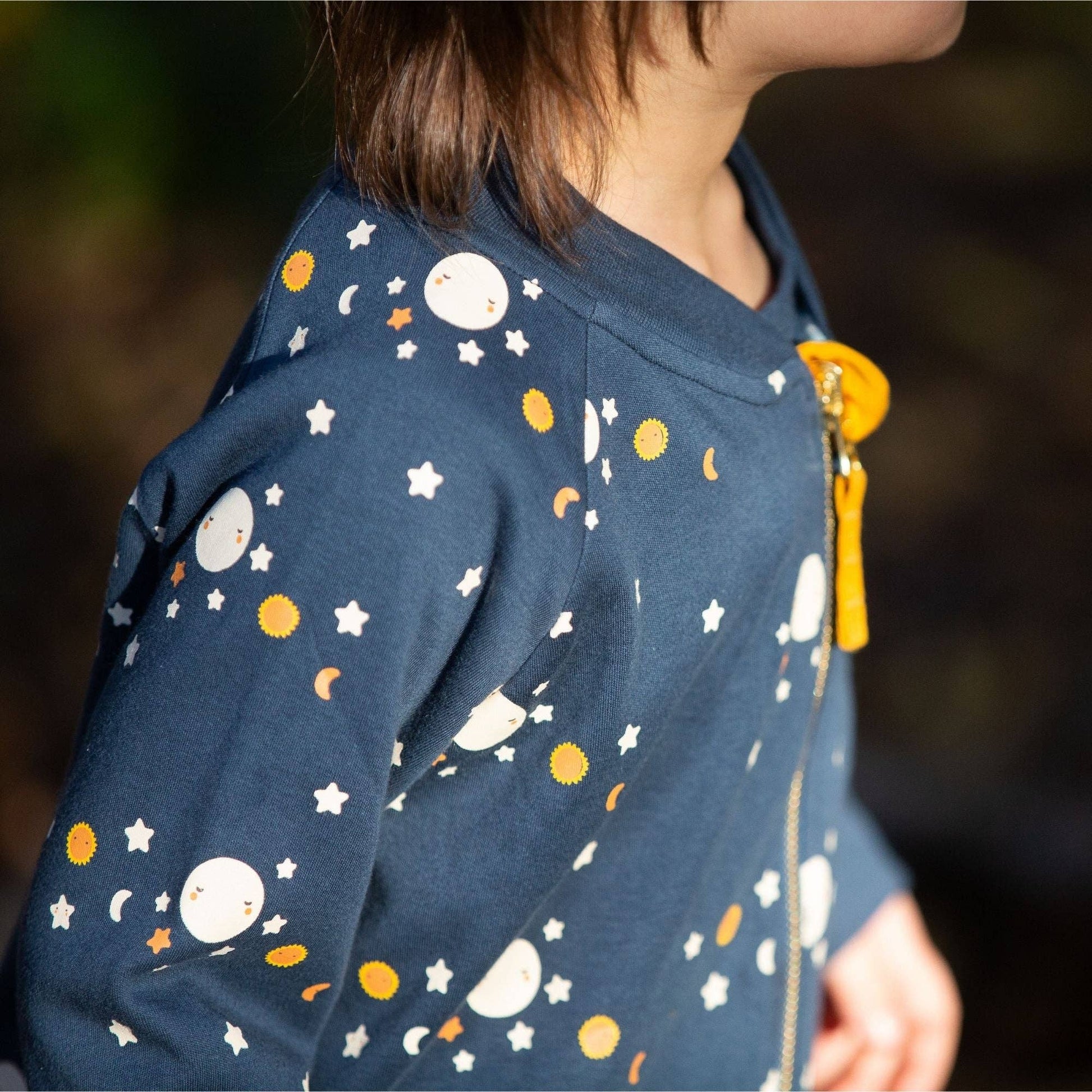 Close-up of a child standing outside wearing a reversible moon jacket