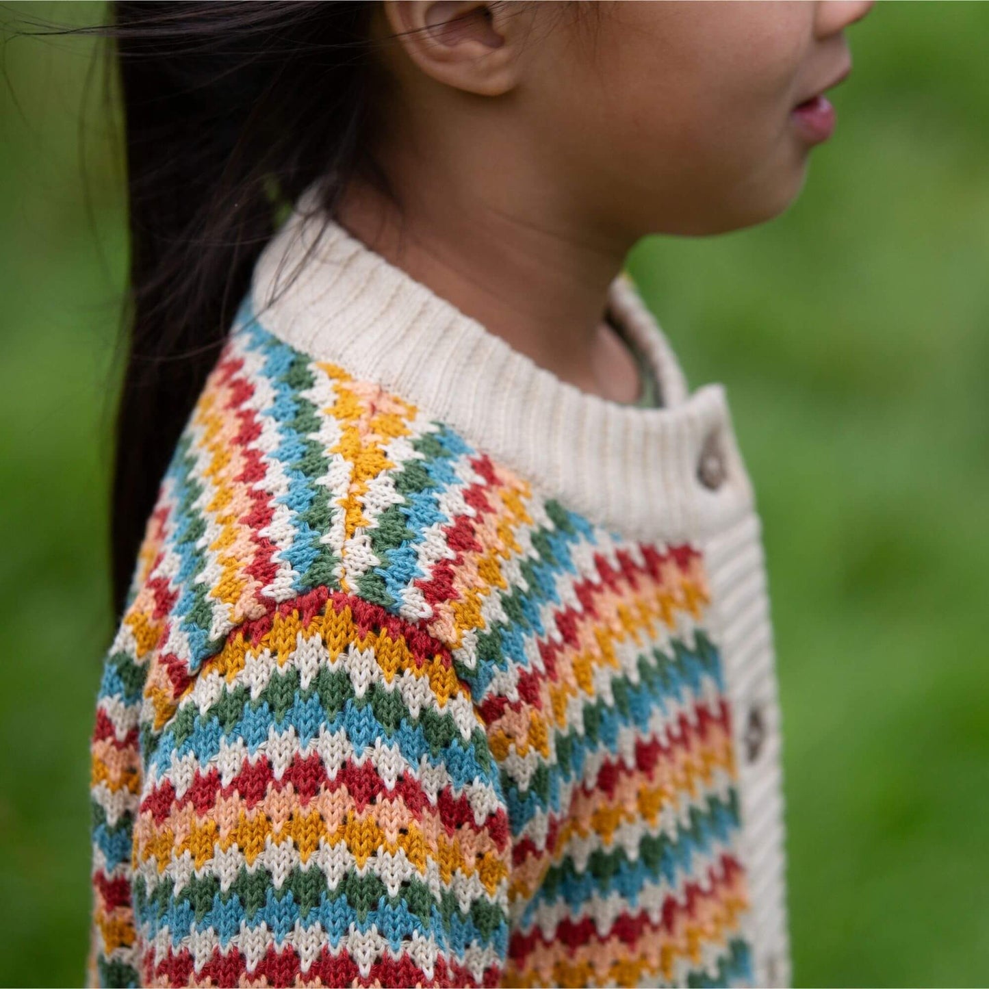 stitch detail on a child wearing organic rainbow knitted cardigan