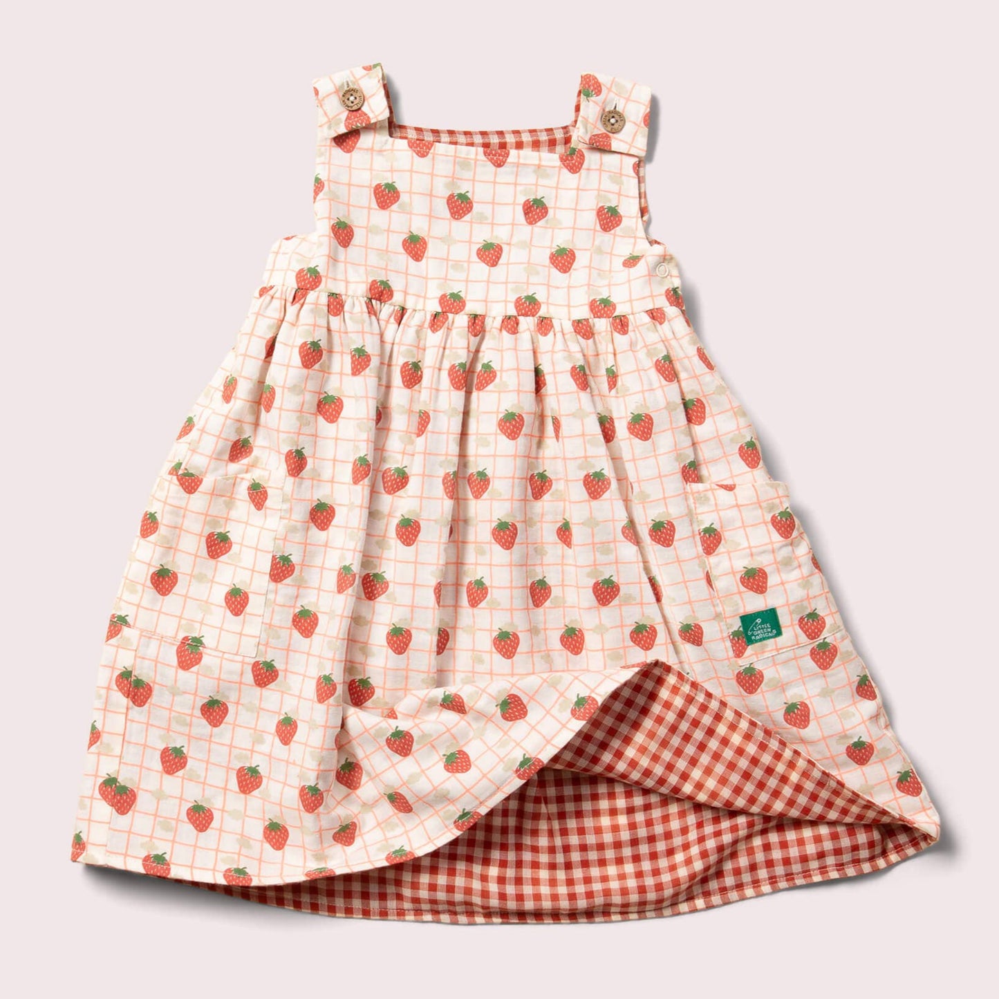 reversible strawberry pinny dress laid flat on the strawberries print side