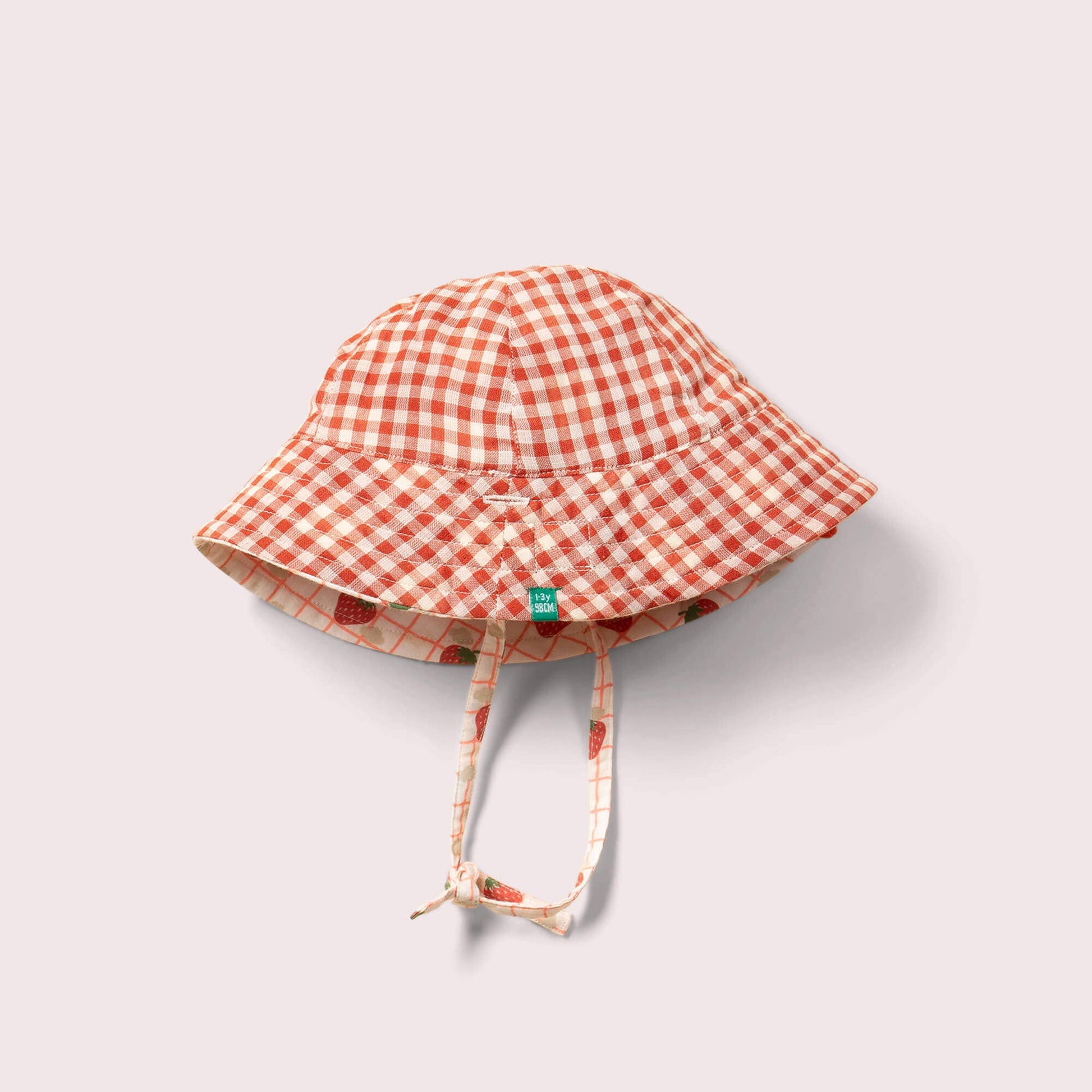 organic reversible strawberry hat laid flat on the red plaid print side