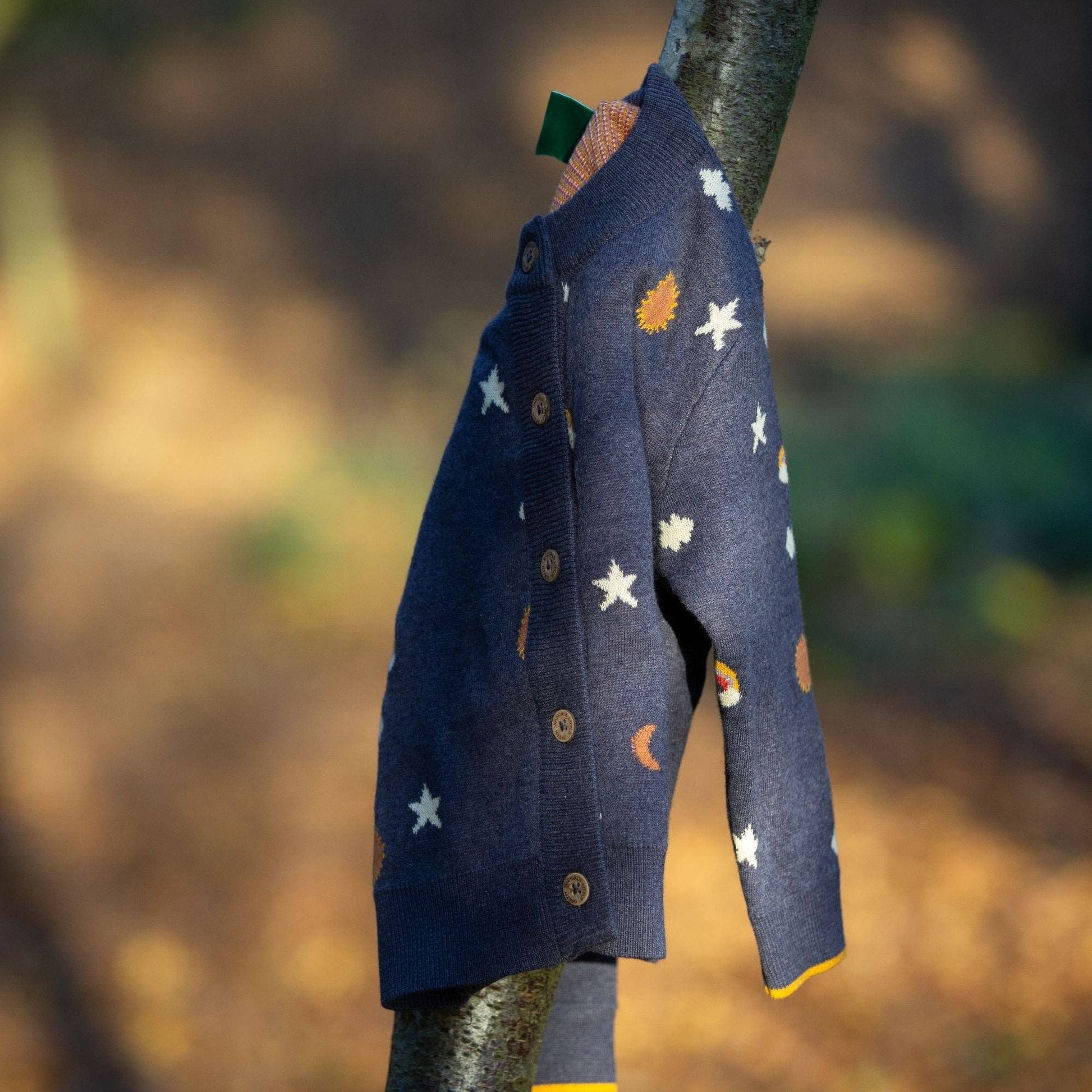 Around the sun organic knitted cardigan hanging from a tree