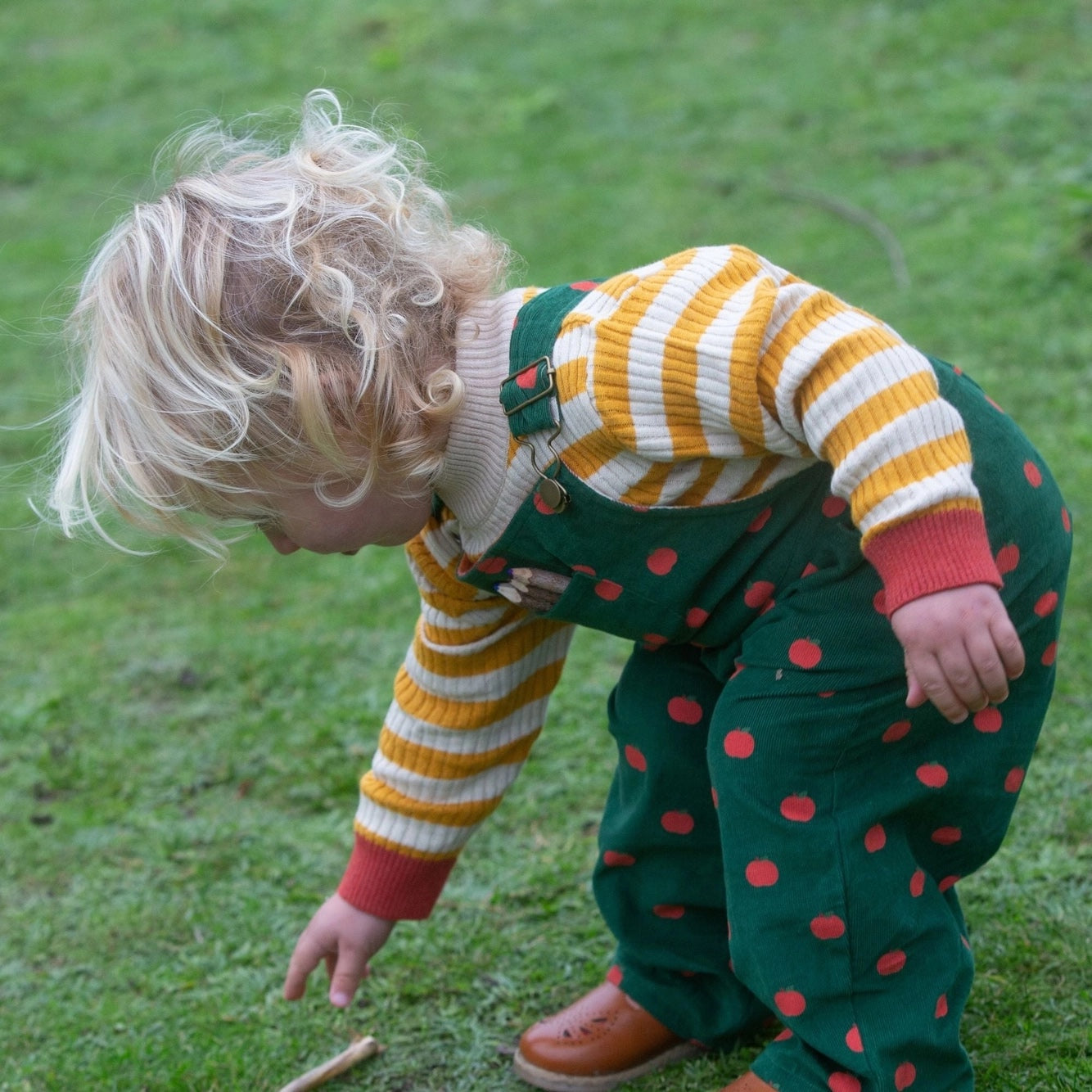 child playing outside wearing apple printed corduroy overalls