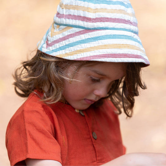 child wearing an orange shirt and a reversible striped sun hat
