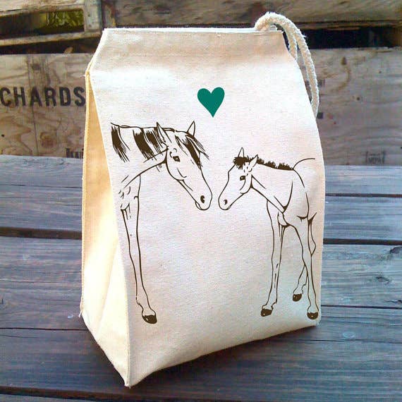 Canvas lunch bag with horses illustrations and a heart on a wooden table