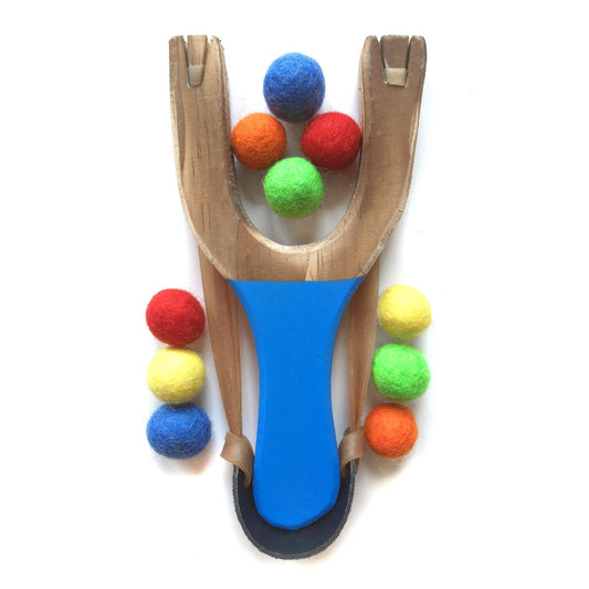 Wooden slingshot with colorful felt balls on a white background