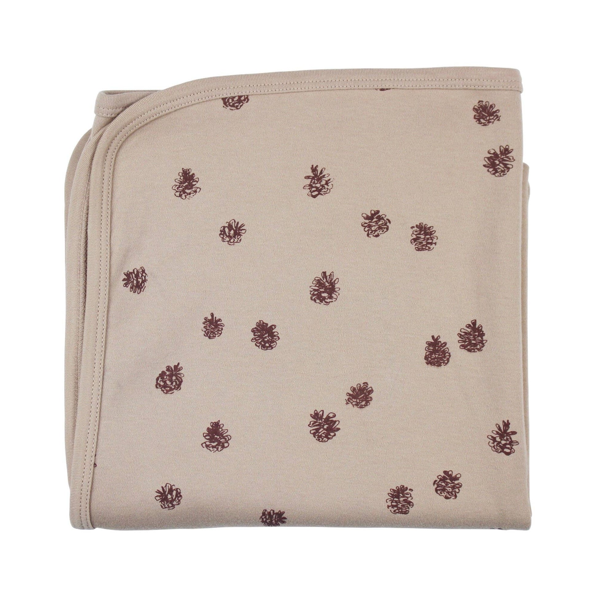 Beige folded baby blanket with pinecones  pattern on a white background