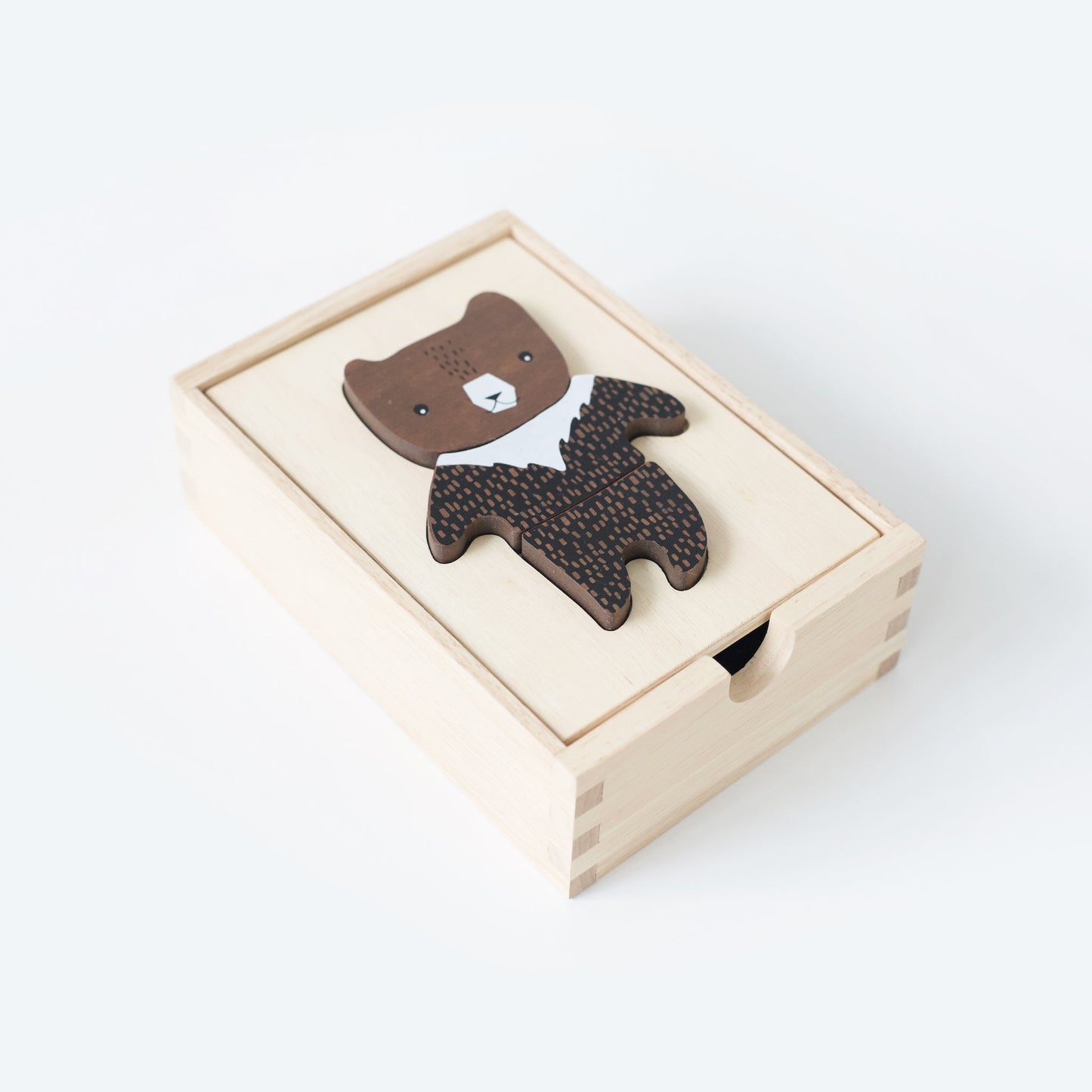 Wooden bear toy with a patterned body in a light wooden box on a white background