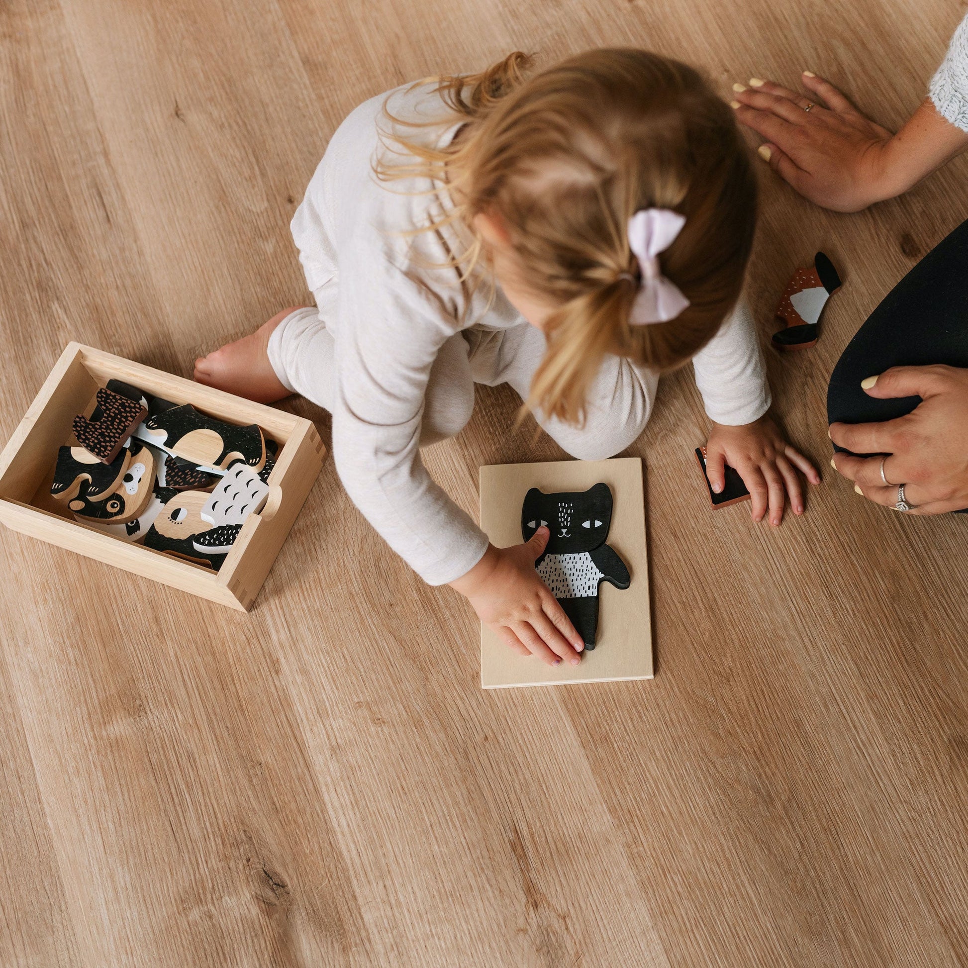Child playing with animal figurines on a wooden floor