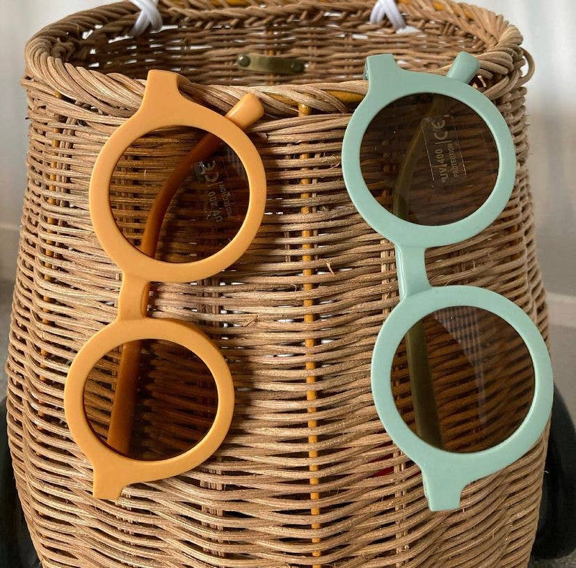 eco sunglasses in orange and green hanging from a straw basket