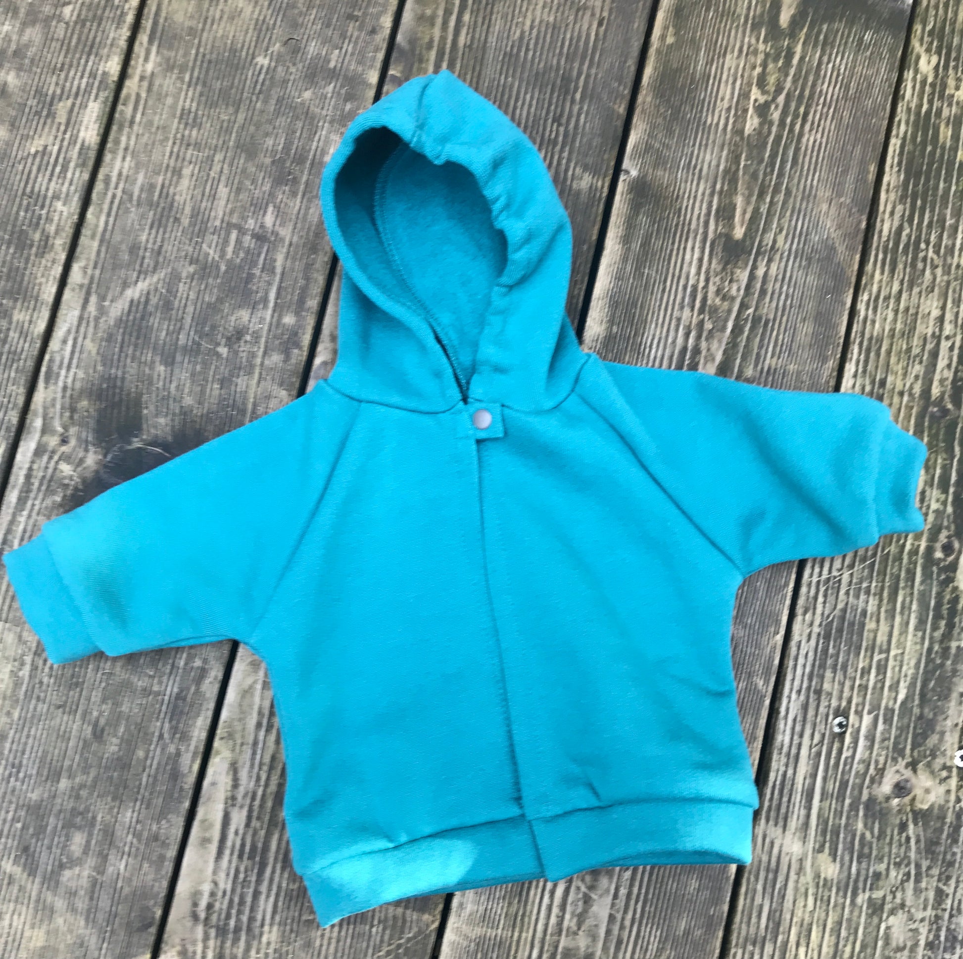 teal fleece hoodie on a wooden surface