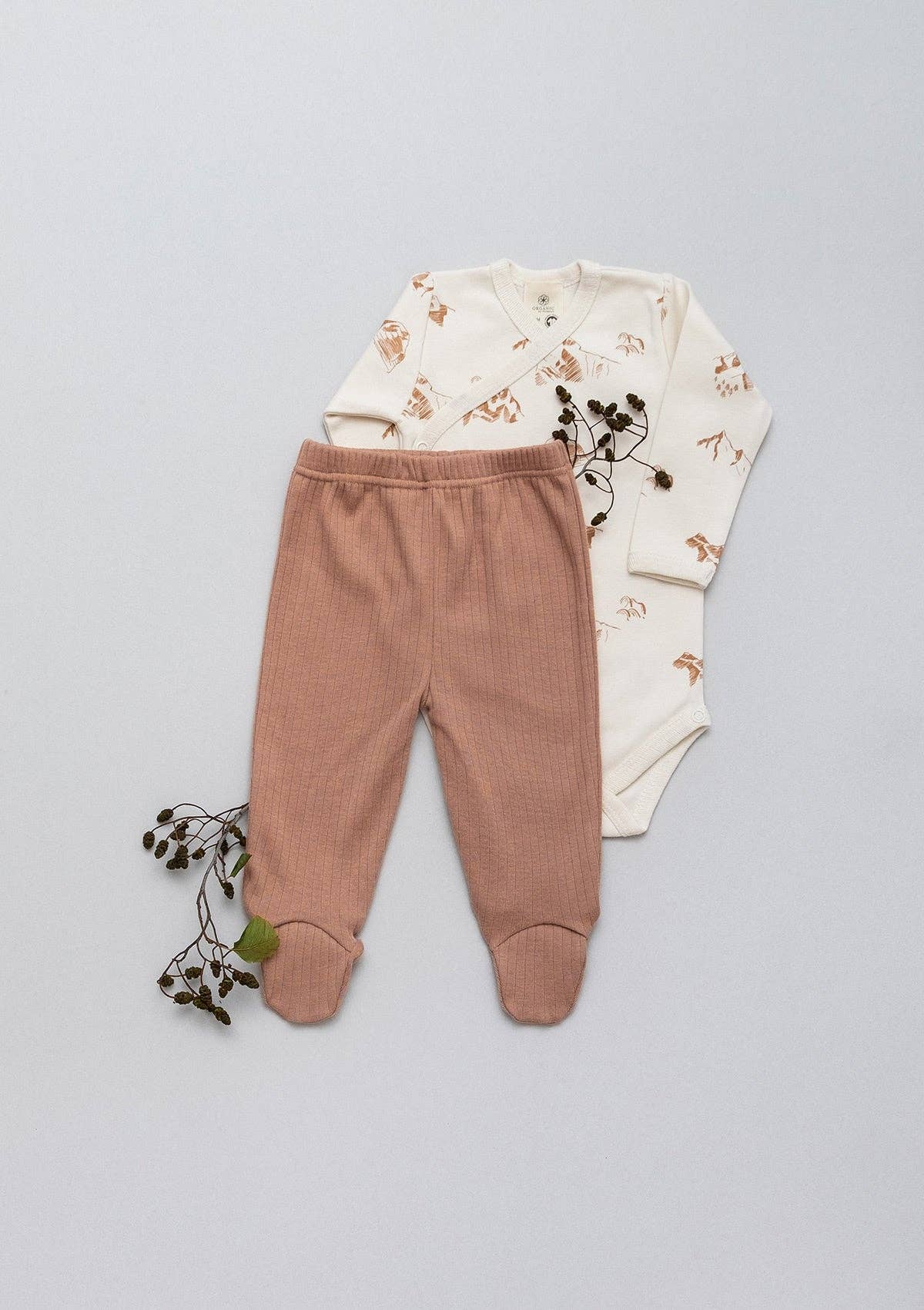 A set of sienna leggings and a onesie laid flat next to flowers