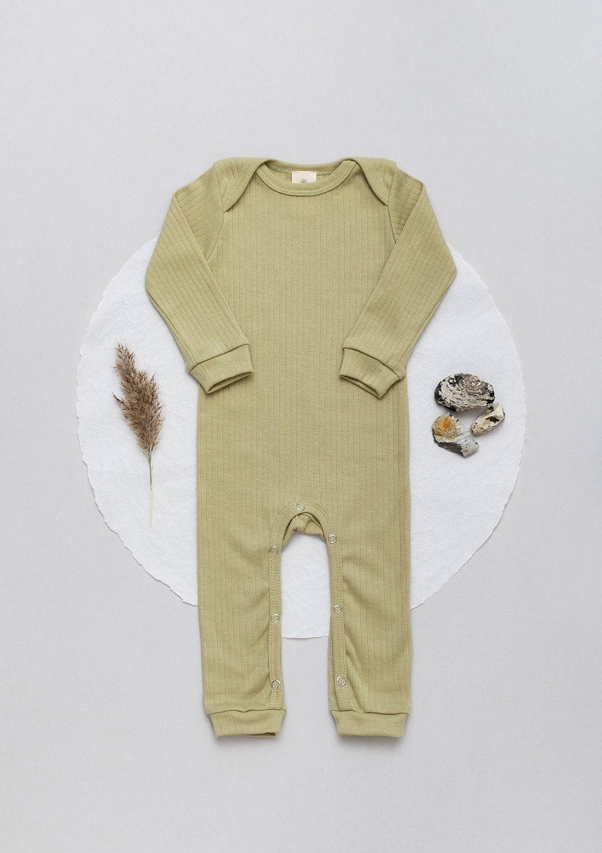 Long sleeve ribbed romper in sage laid flat next to a leaf and stones