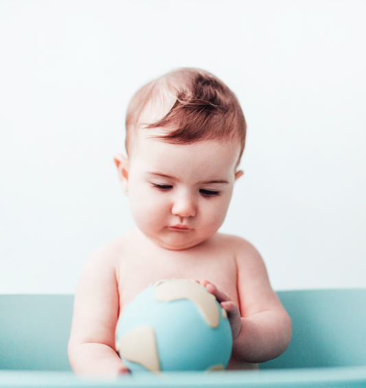 a baby holding a natural rubber Earthy the World Ball