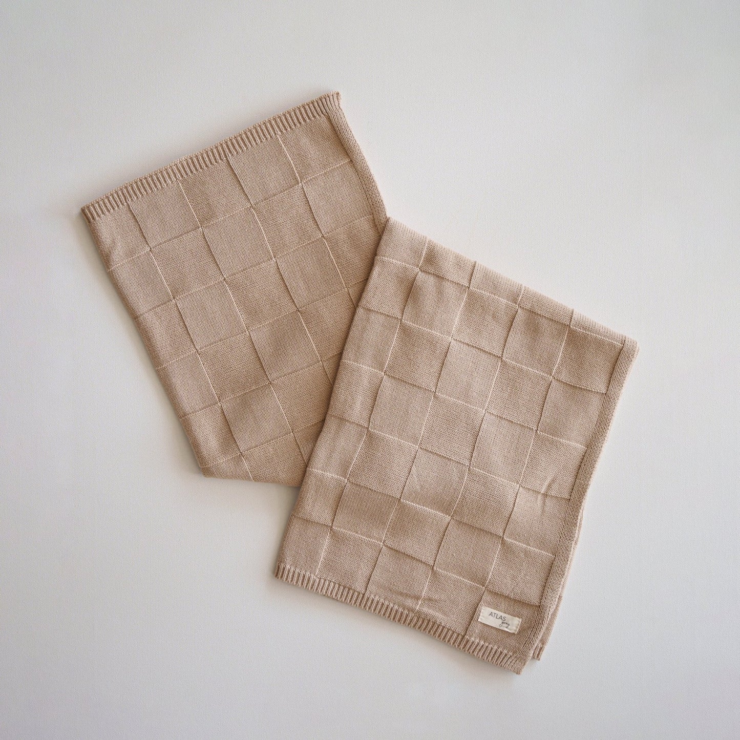 Two beige woven scarves on a light gray background