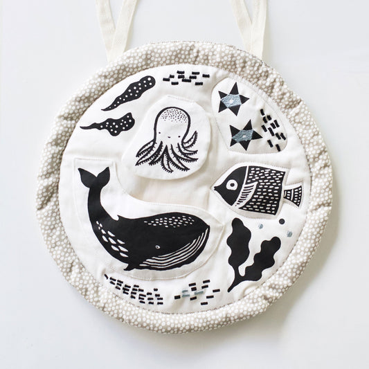 Round white plate with black and gray sea-themed illustrations on a white background