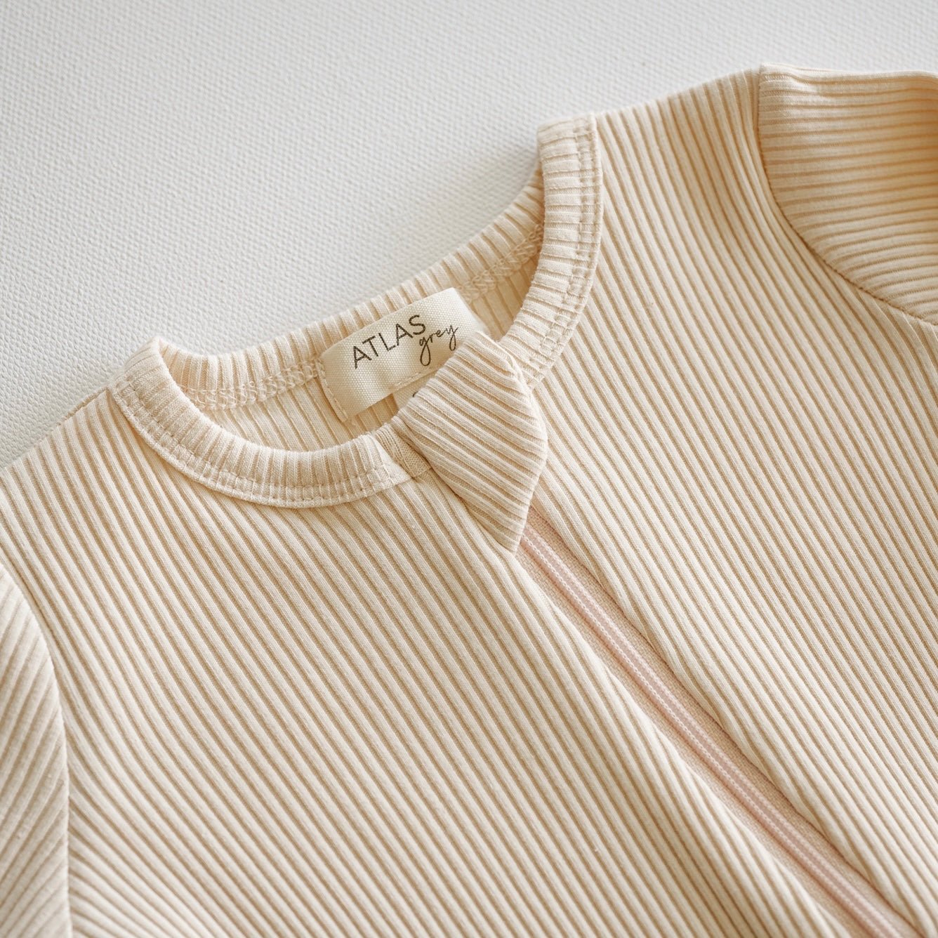 Beige ribbed sweater with 'Atlas' label on a light background