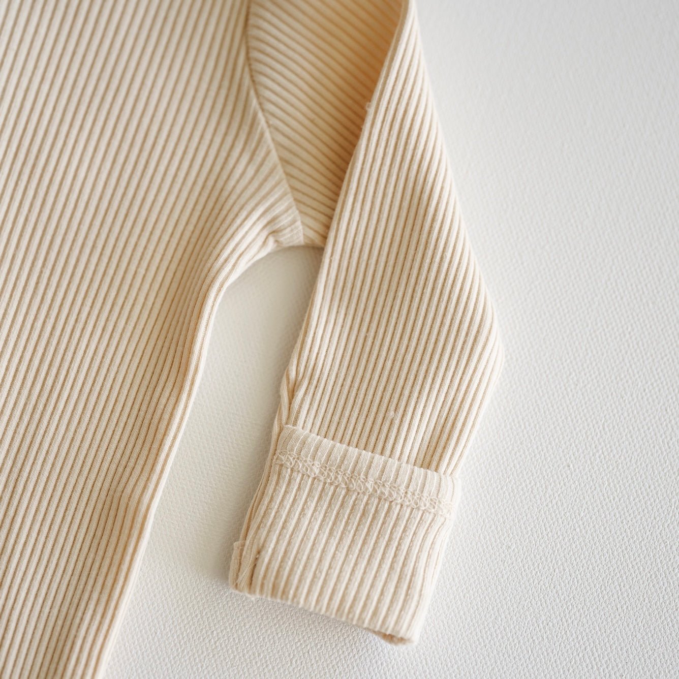 Close-up of a beige ribbed sweater on a white background