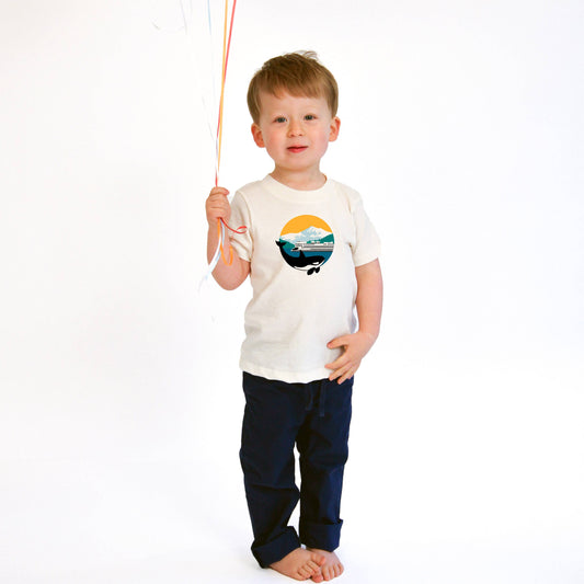 a child holding balloons on a string wearing a mountain and ferry organic short sleeve tee